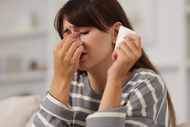 Photo of Woman with napkin suffering from sinusitis on sofa at home