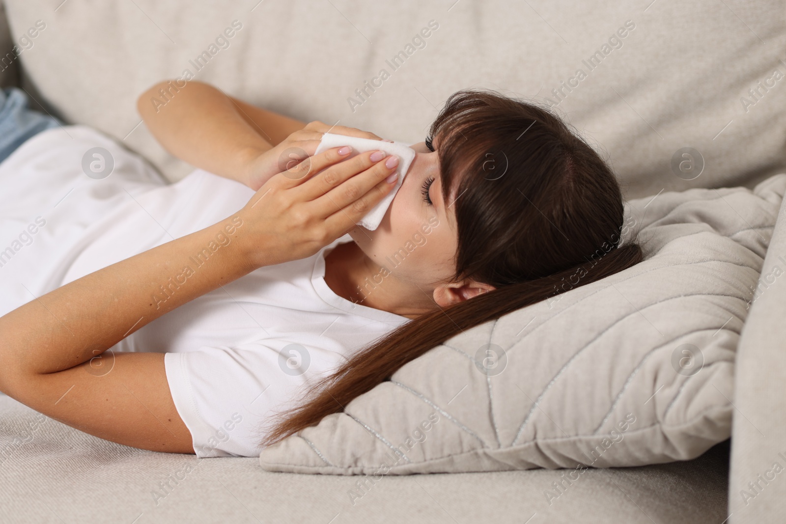 Photo of Woman with napkin suffering from sinusitis on sofa at home