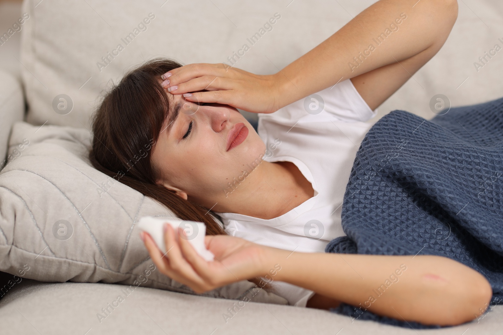 Photo of Woman with napkin suffering from sinusitis on sofa at home