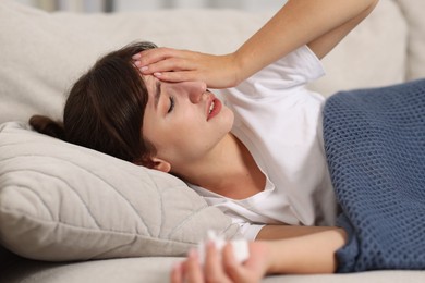 Woman with napkin suffering from sinusitis on sofa at home