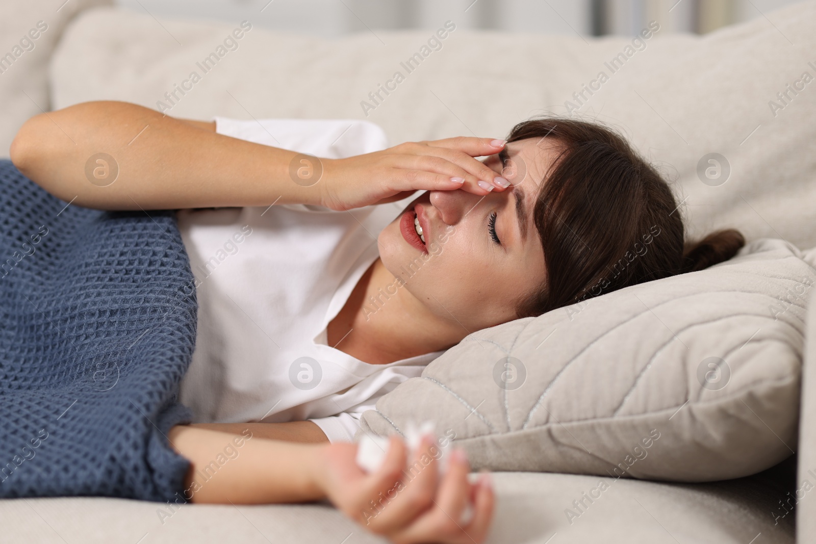 Photo of Woman with napkin suffering from sinusitis on sofa at home