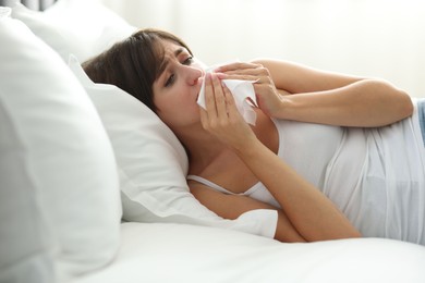 Photo of Woman with napkin suffering from sinusitis on bed