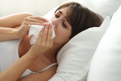 Photo of Woman with napkin suffering from sinusitis on bed