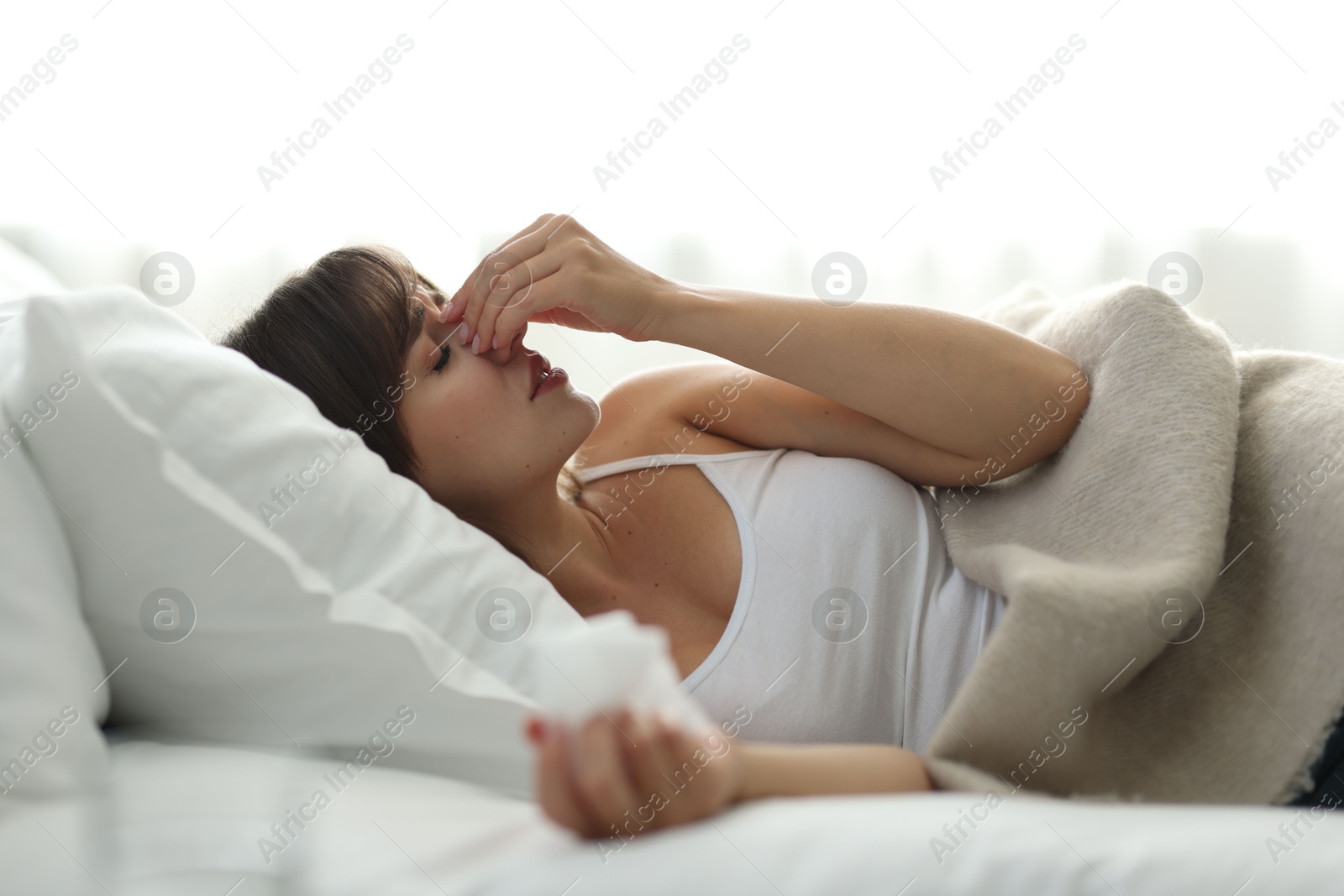 Photo of Woman with napkin suffering from sinusitis on bed