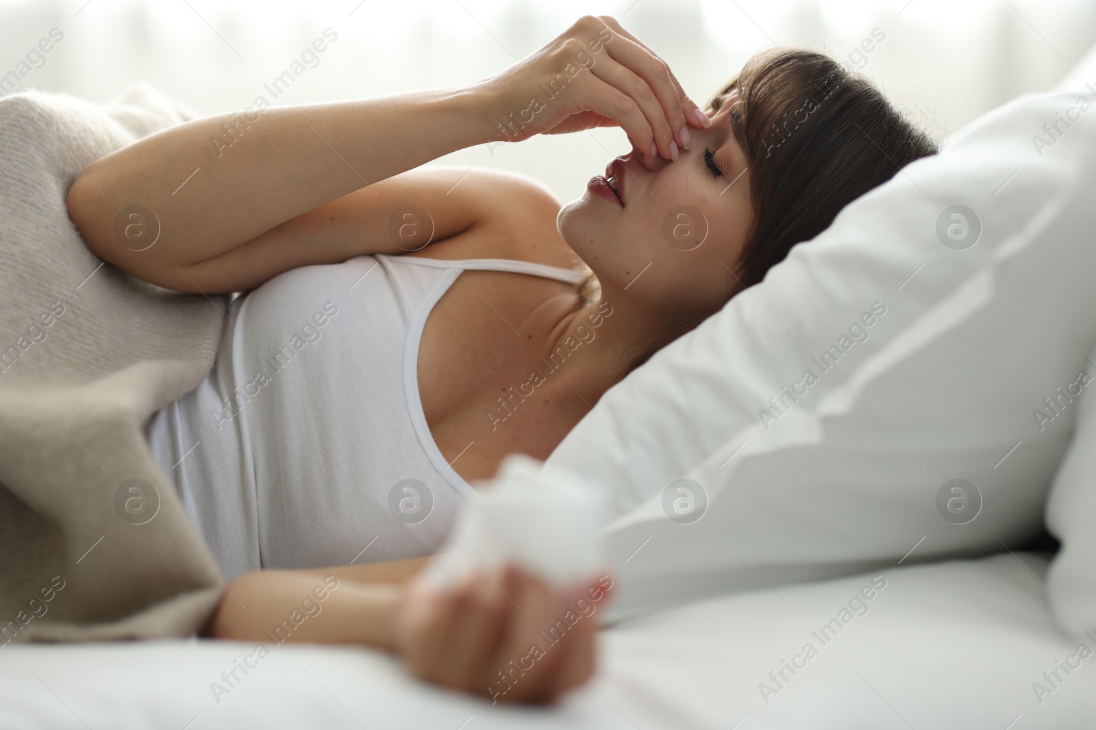 Photo of Woman with napkin suffering from sinusitis on bed