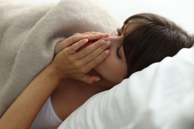 Woman suffering from sinusitis in bed indoors