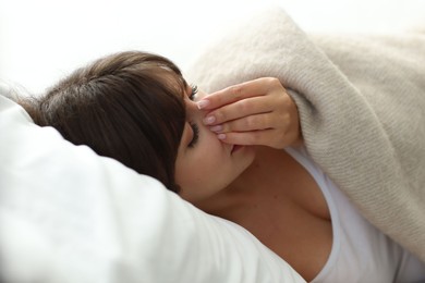 Woman suffering from sinusitis in bed indoors