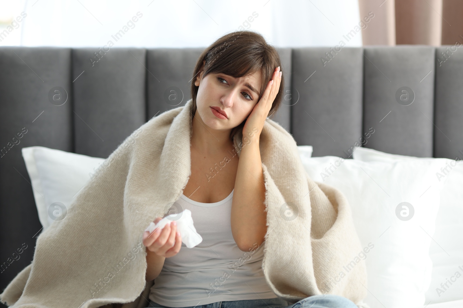 Photo of Woman wrapped in blanket suffering from sinusitis on bed