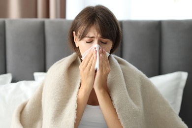 Woman wrapped in blanket suffering from sinusitis at home