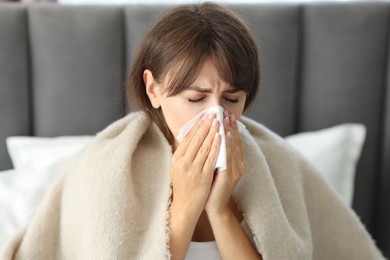 Woman wrapped in blanket suffering from sinusitis at home