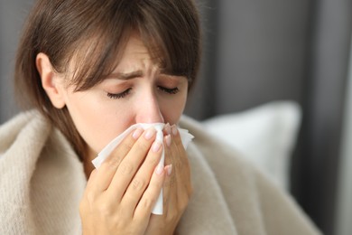 Woman wrapped in blanket suffering from sinusitis at home