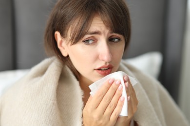 Woman wrapped in blanket suffering from sinusitis at home