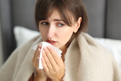 Woman wrapped in blanket suffering from sinusitis at home