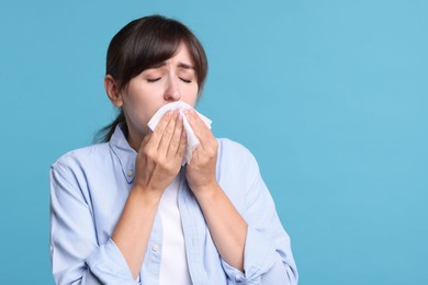 Photo of Woman with napkin suffering from sinusitis on light blue background. Space for text