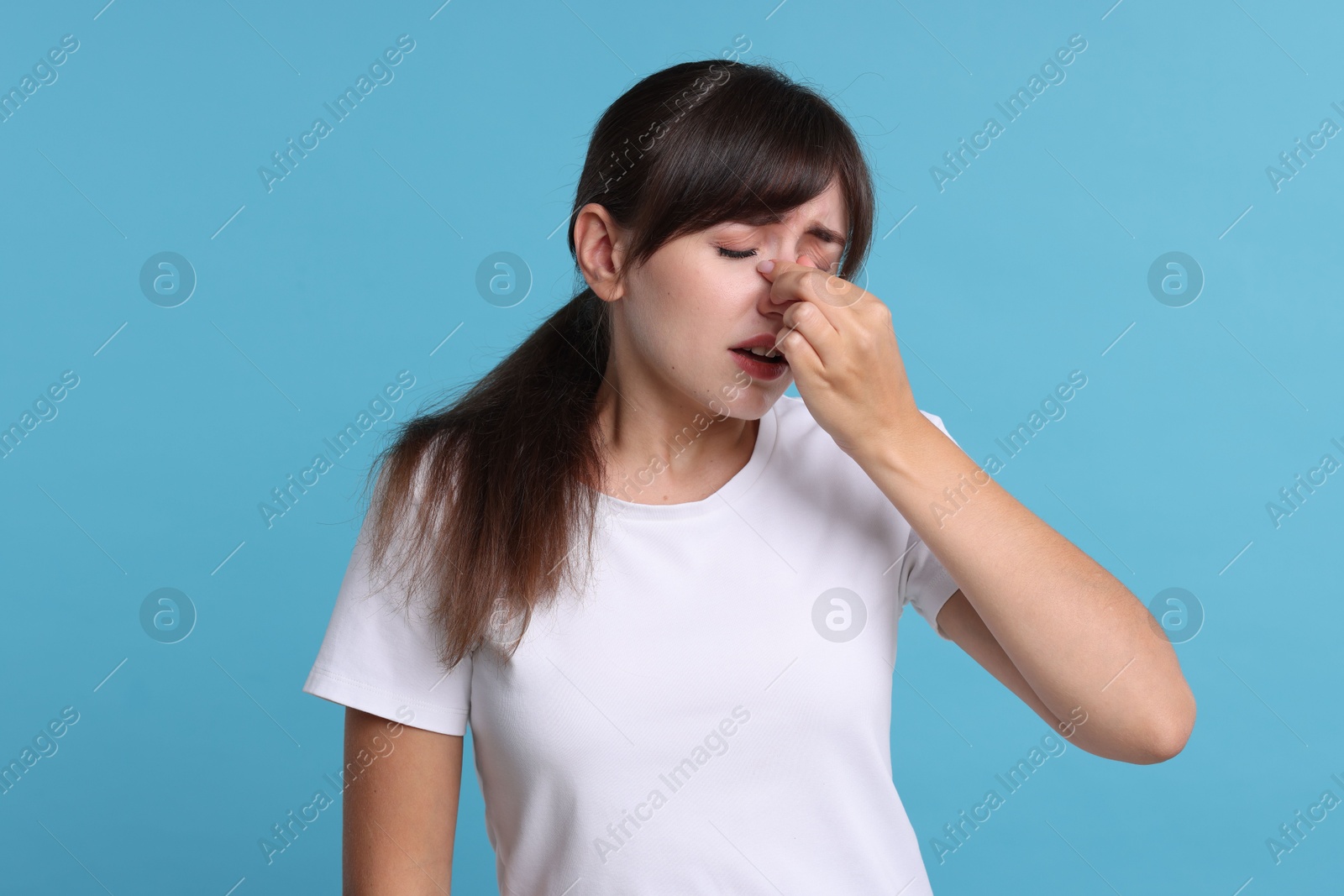 Photo of Woman suffering from sinusitis on light blue background