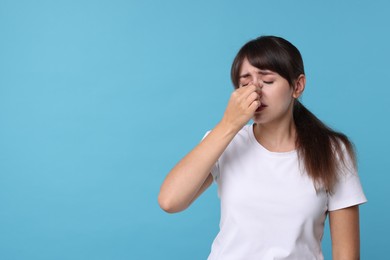 Photo of Woman suffering from sinusitis on light blue background. Space for text