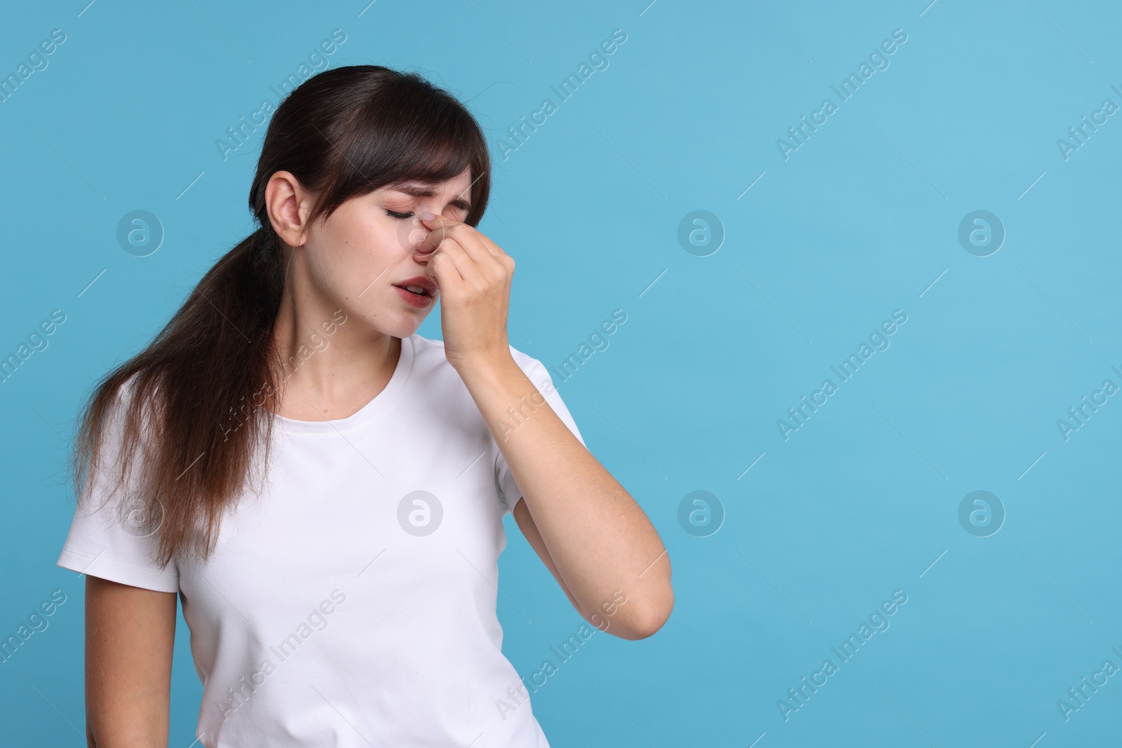 Photo of Woman suffering from sinusitis on light blue background. Space for text