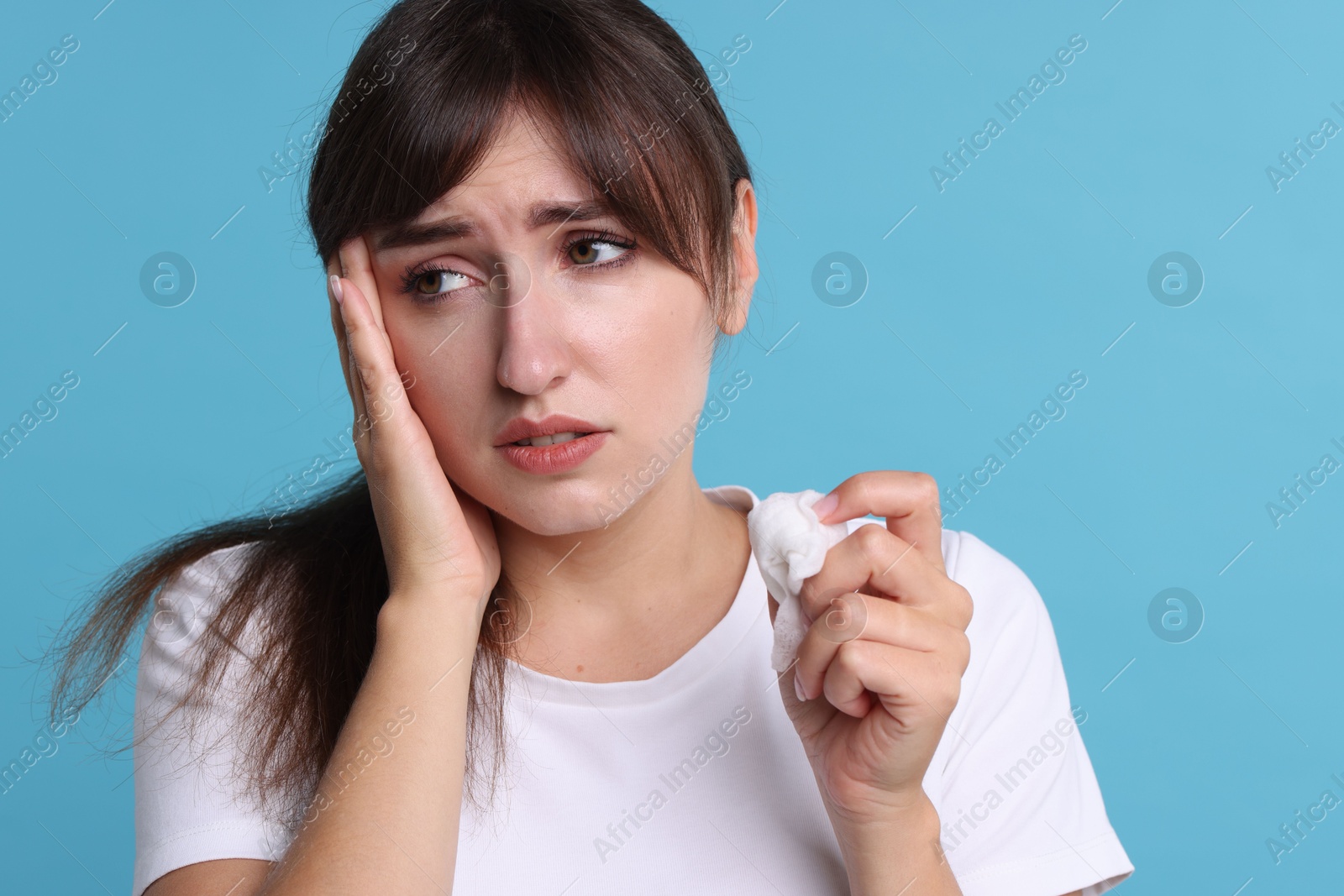 Photo of Woman with napkin suffering from sinusitis on light blue background