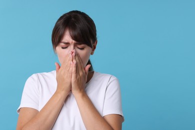 Photo of Woman suffering from sinusitis on light blue background. Space for text