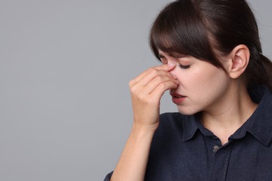 Woman suffering from sinusitis on grey background. Space for text