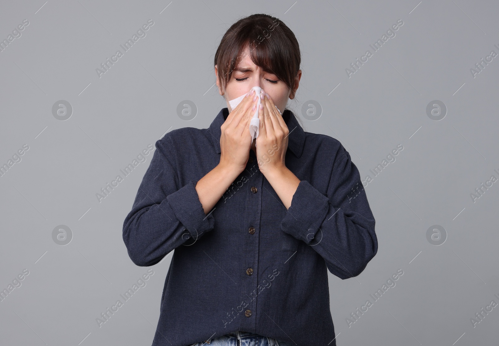 Photo of Woman with napkin suffering from sinusitis on grey background