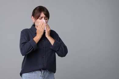 Photo of Woman with napkin suffering from sinusitis on grey background. Space for text