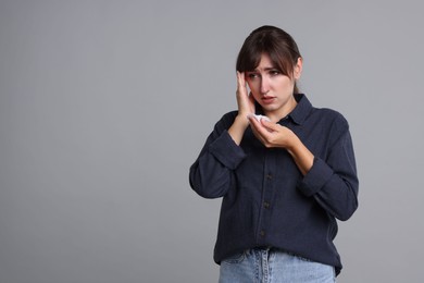 Photo of Woman with napkin suffering from sinusitis on grey background. Space for text