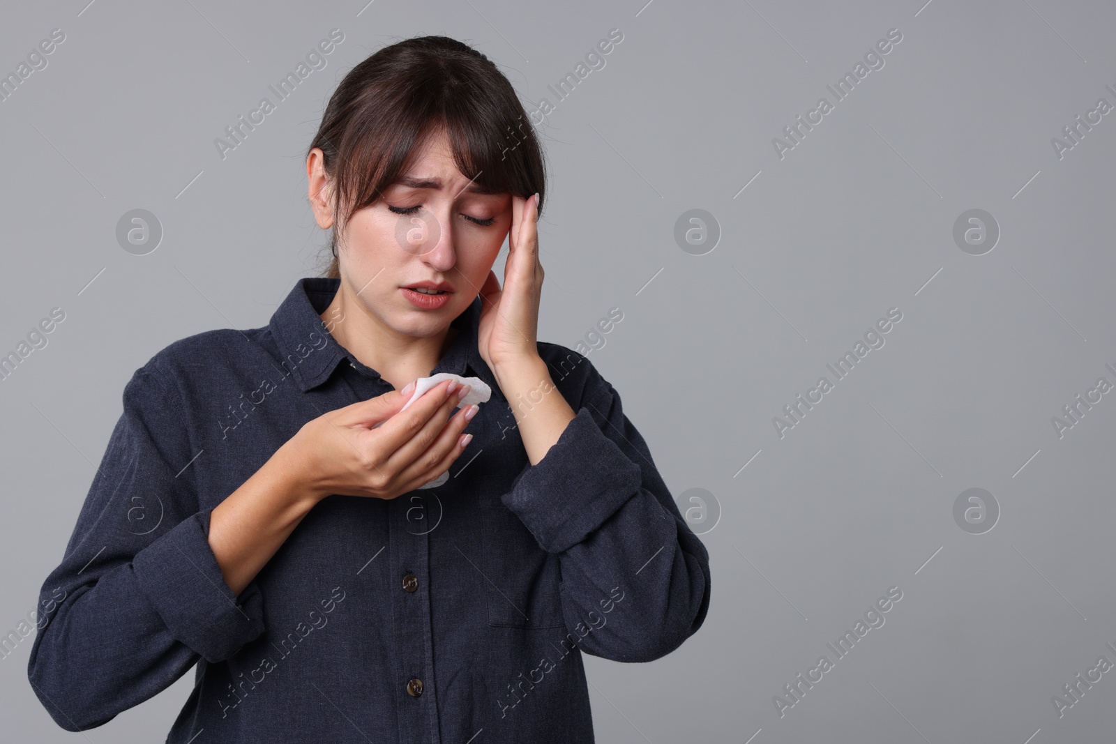 Photo of Woman with napkin suffering from sinusitis on grey background. Space for text