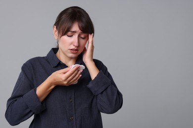 Photo of Woman with napkin suffering from sinusitis on grey background. Space for text