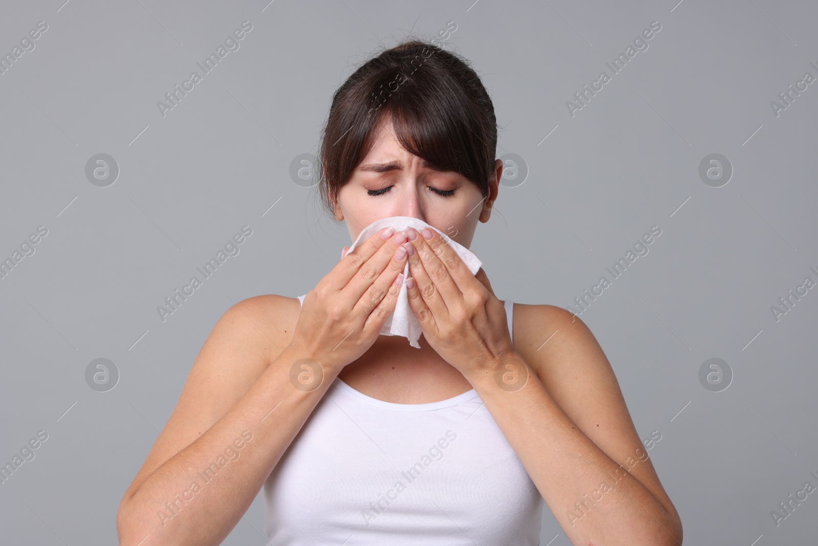 Photo of Woman with napkin suffering from sinusitis on grey background