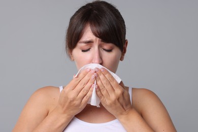 Photo of Woman with napkin suffering from sinusitis on grey background