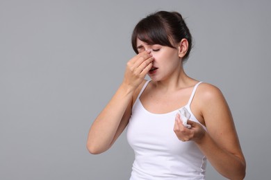 Woman with napkin suffering from sinusitis on grey background. Space for text