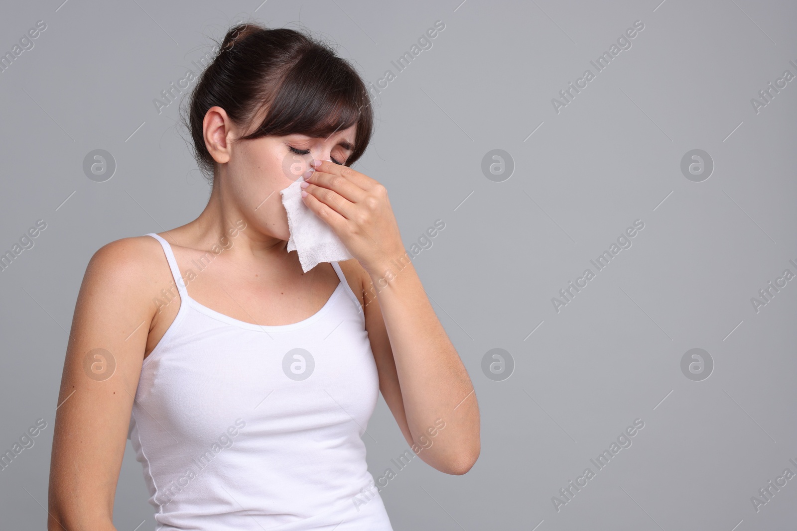 Photo of Woman with napkin suffering from sinusitis on grey background. Space for text