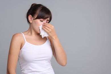 Woman with napkin suffering from sinusitis on grey background. Space for text