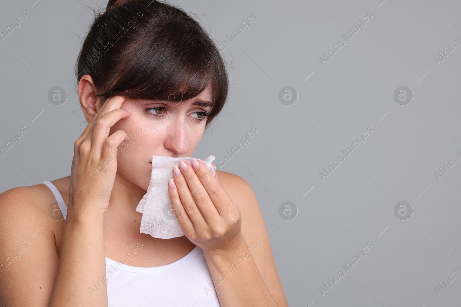 Photo of Woman with napkin suffering from sinusitis on grey background. Space for text