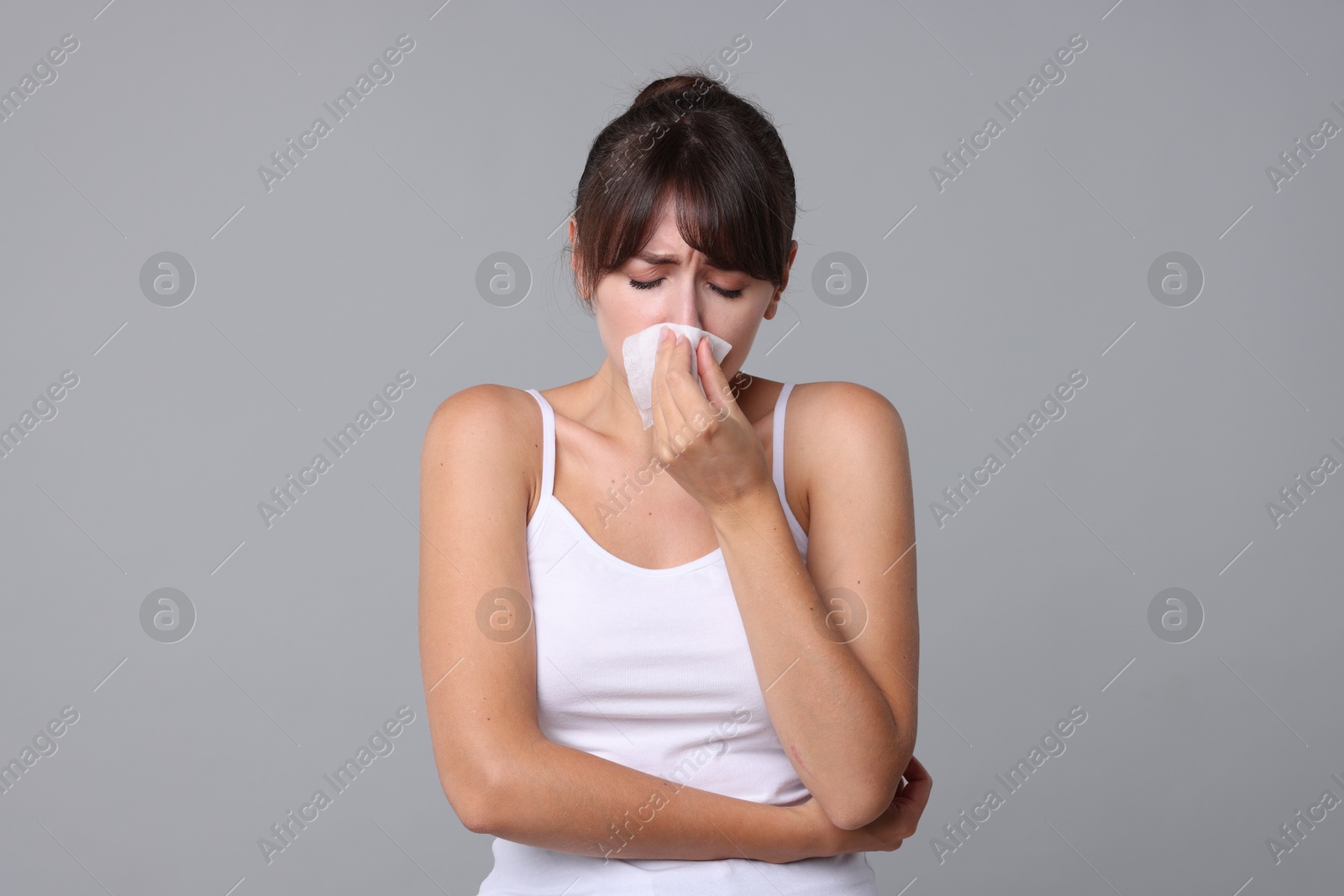 Photo of Woman with napkin suffering from sinusitis on grey background