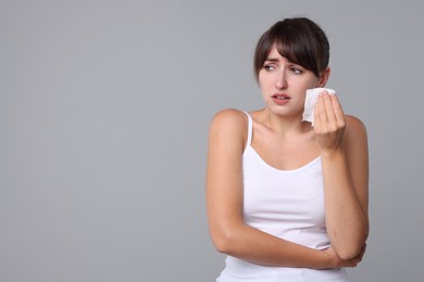 Woman with napkin suffering from sinusitis on grey background. Space for text