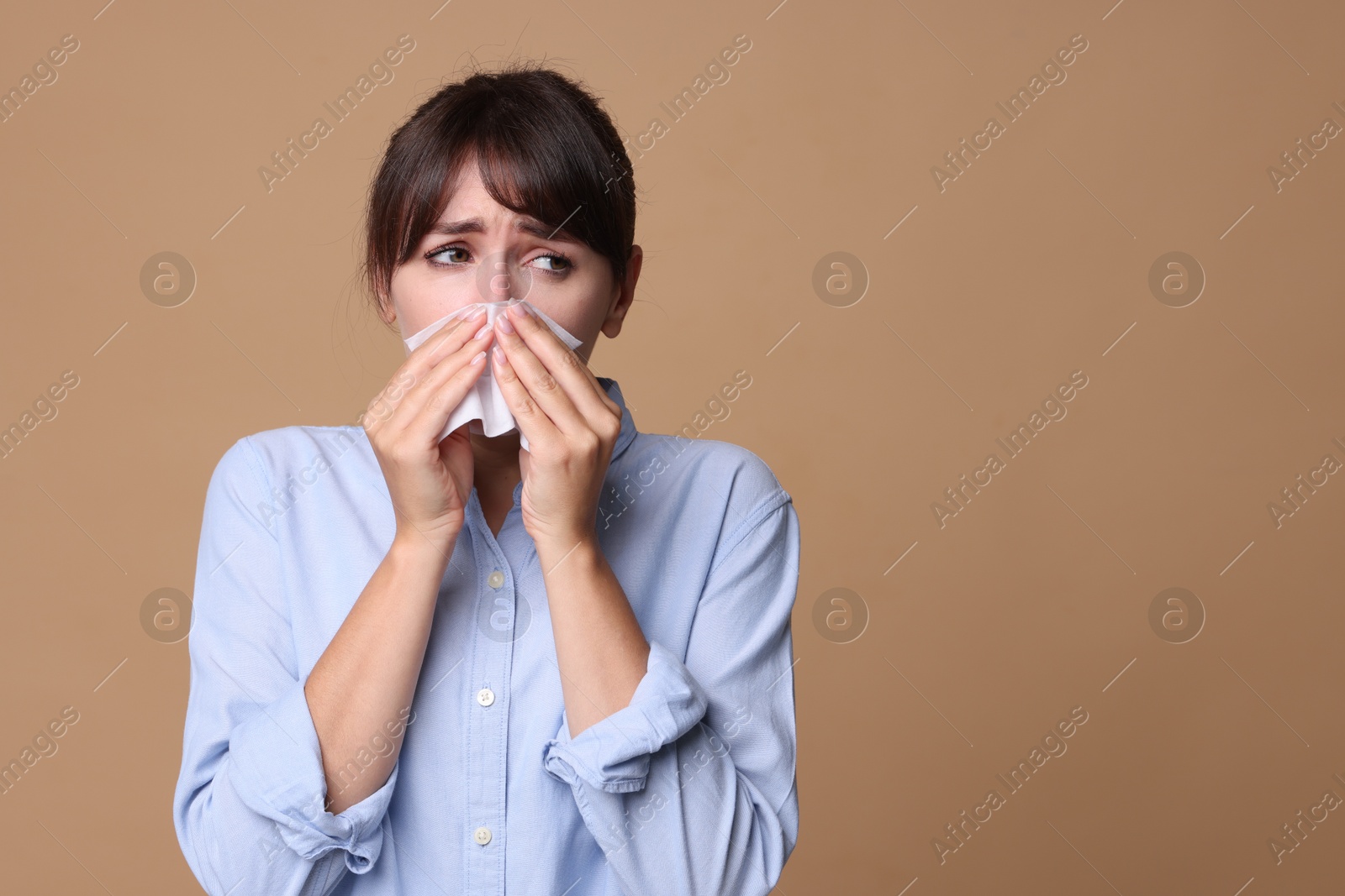 Photo of Woman with napkin suffering from sinusitis on beige background. Space for text