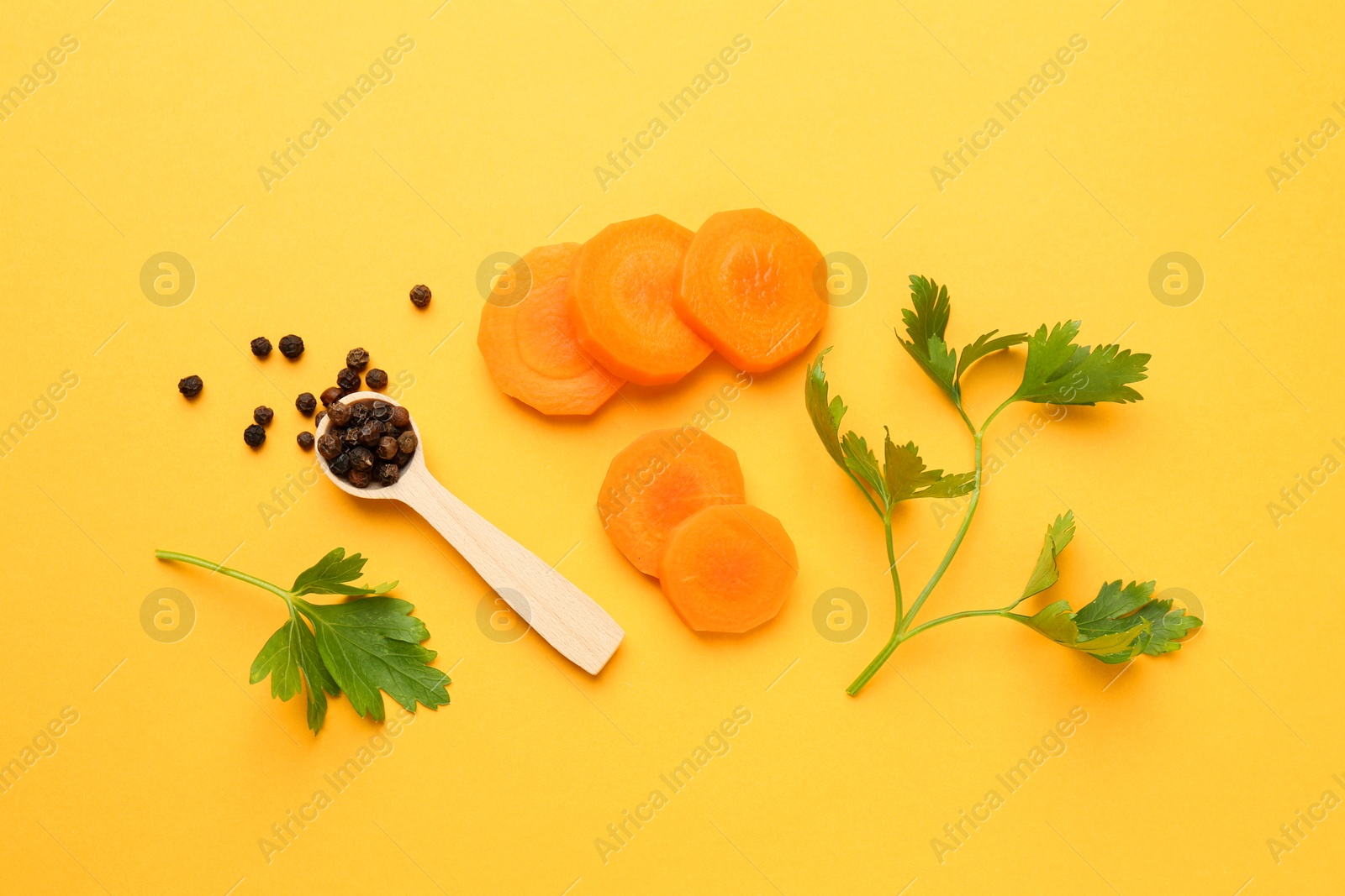 Photo of Slices of fresh ripe carrot, spices and spoon on yellow background, flat lay