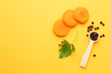 Photo of Slices of fresh ripe carrot, spices and spoon on yellow background, flat lay. Space for text