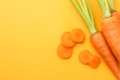 Photo of Whole and cut carrots on yellow background, flat lay. Space for text