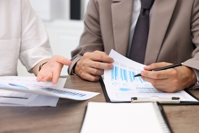 Photo of Consultant working with client at wooden table in office, closeup. Business meeting