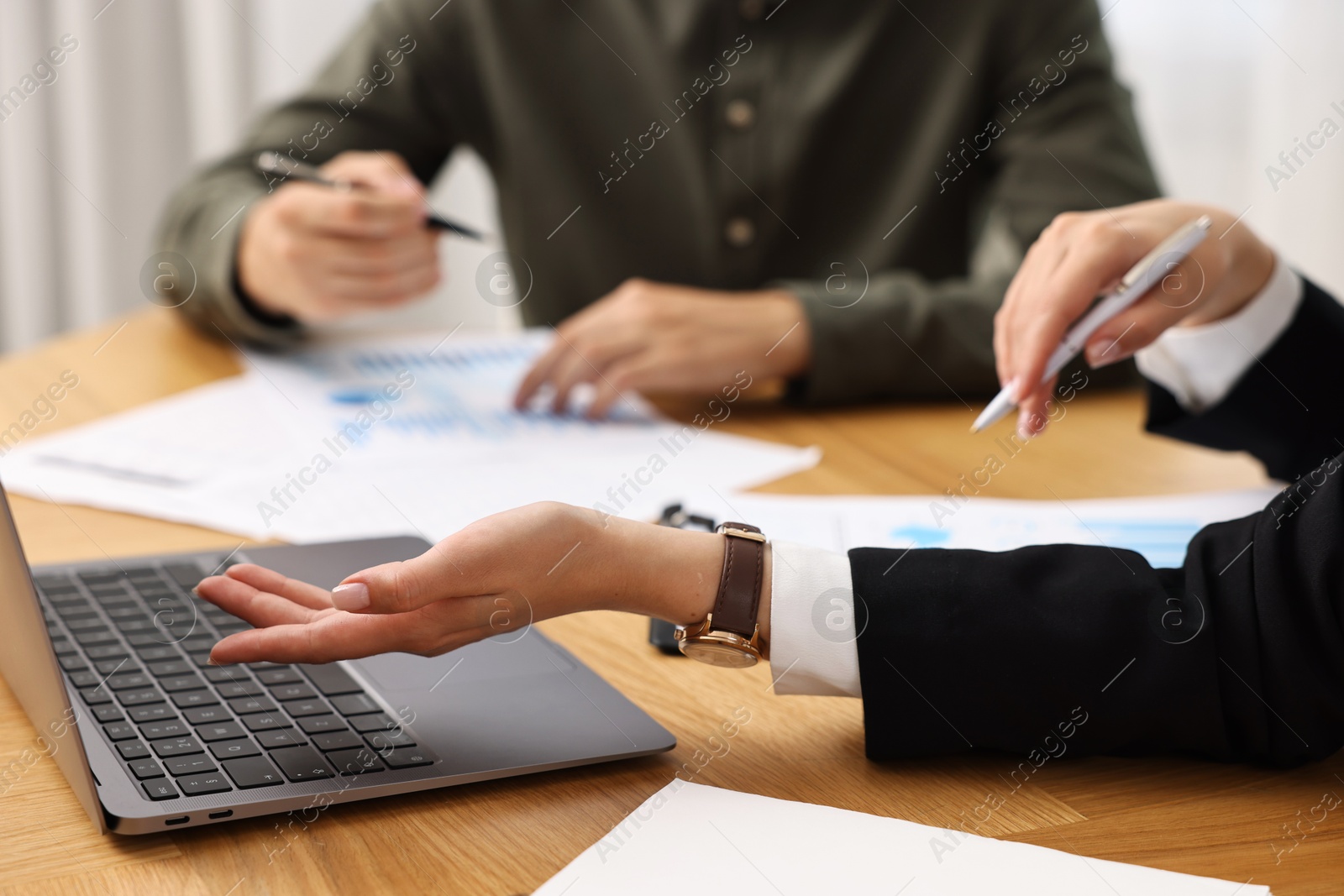 Photo of Consultant working with client at wooden table in office, closeup. Business meeting