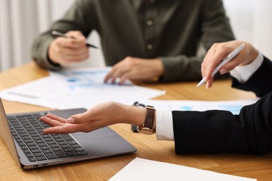 Consultant working with client at wooden table in office, closeup. Business meeting