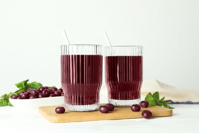 Photo of Delicious acai juice in glasses, berries and mint on white wooden table