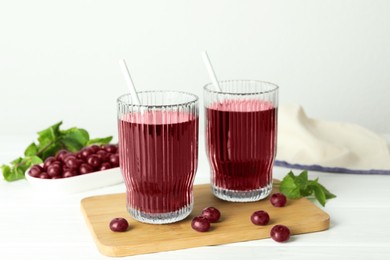 Photo of Delicious acai juice in glasses, berries and mint on white wooden table