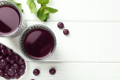 Photo of Delicious acai juice in glasses, berries and mint on white wooden table, flat lay. Space for text