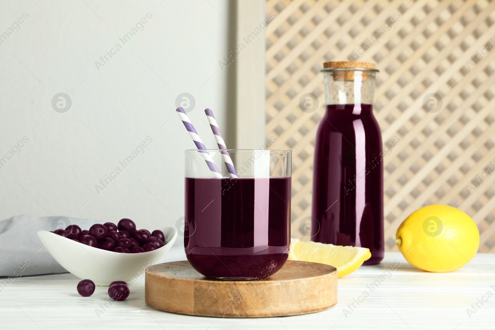 Photo of Delicious acai juice, berries and lemon on white wooden table