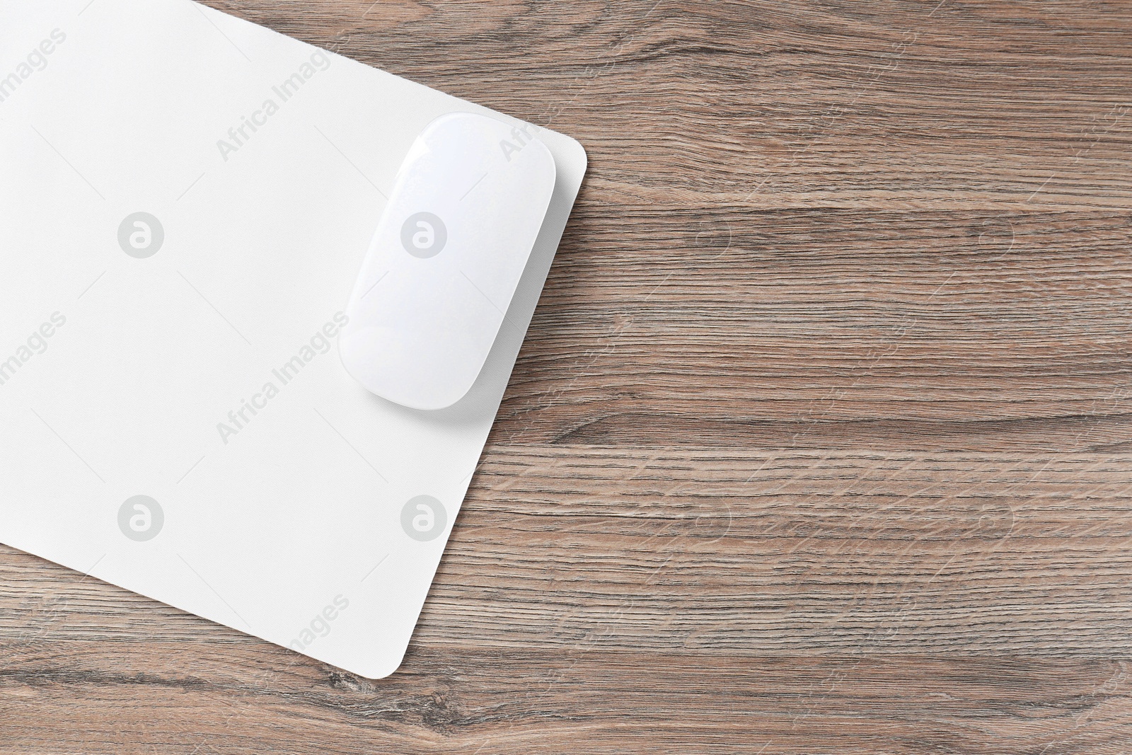 Photo of Computer mouse with mousepad on wooden desk, top view. Space for text