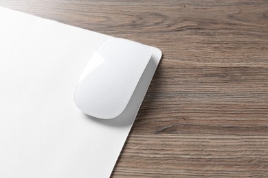 Photo of Computer mouse with mousepad on wooden desk, closeup. Space for text